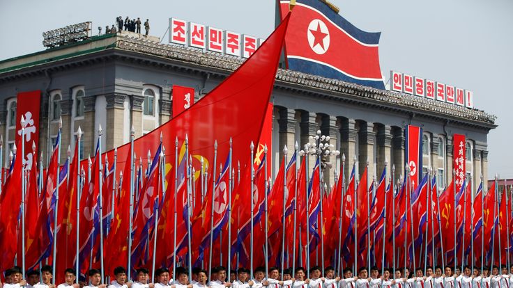 Men carry flags in front of the stand with North Korean leader Kim Jong Un 