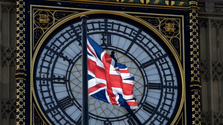 A Union Flag flies in front of the Big Ben clock face abover the Houses of Parliament