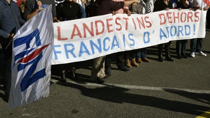 Front National supporters wave a banner reading 'Illigal immigrants out, French citizens first'