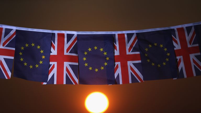 The EU and UK flags fly on a line at sunset
