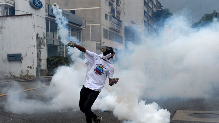 A demonstrator throws a tear gas grenade back at police during a march against Mr Maduro