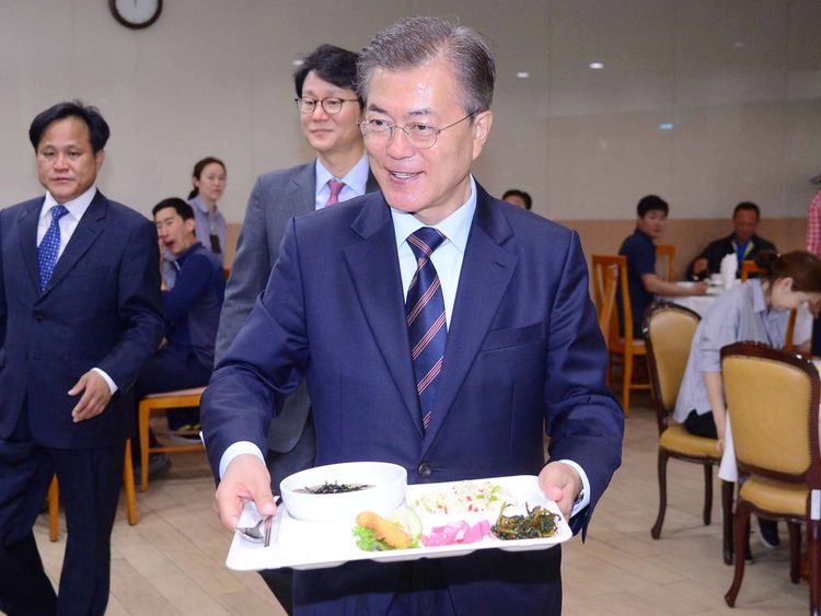 South Korean President Moon Jae-in carries a food tray in a Seoul staff canteen