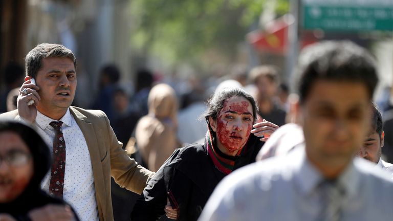 An injured woman is helped away from the blast site
