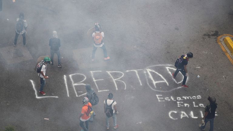 Opposition supporters paint a graffiti that reads "Freedom" while rallying against President Nicolas Maduro in Caracas, Venezuela