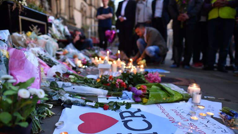 People pause in front of candles and messages set up in front of floral tributes in Albert Square in Manchester in solidarity with those killed and injured