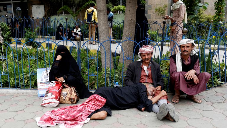 Relatives sit with a sick man waiting to be admitted to a hospital in Sanaa