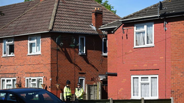 Police on duty outside a house (R) in Fallowfield, Manchester, which they earlier raided