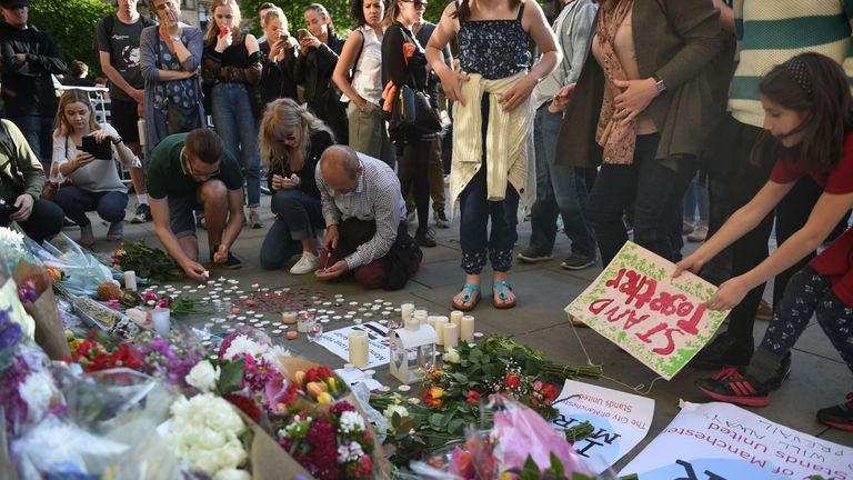 People pile up flowers and arrange candles in tribute to those who have died