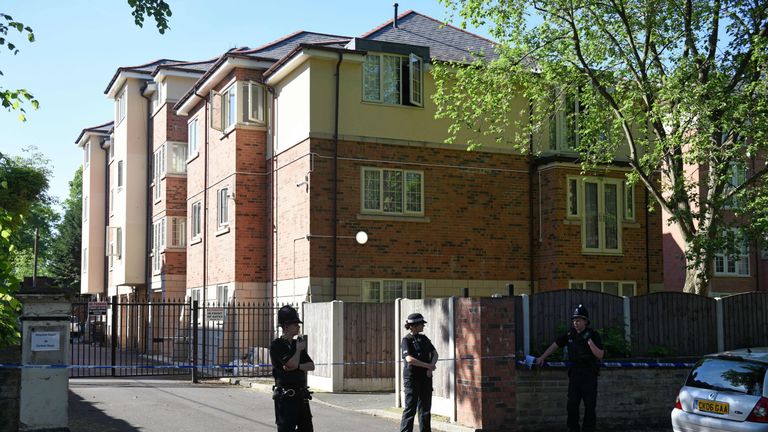 Police officers stand on duty by a cordoned of block of flats in Whalley Range, which was also raided