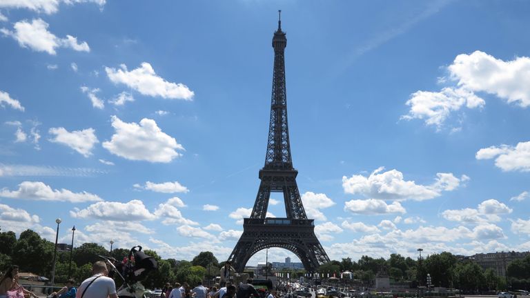 People enjoy a sunny day next to the Trocadero fountains, in front of the Eiffel Tower