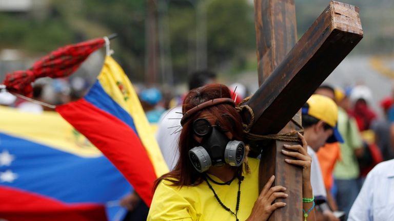An opposition supporter carrying a cross attends a rally against Venezuela&#39;s President Nicolas Maduro in Caracas