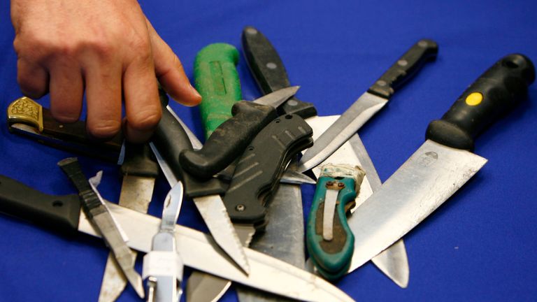 A Metropolitan Police representative arranges knives, seized in recent operations, for photographers after a news conference about knife crime, at New Scotland Yard, in central London on May 29, 2008