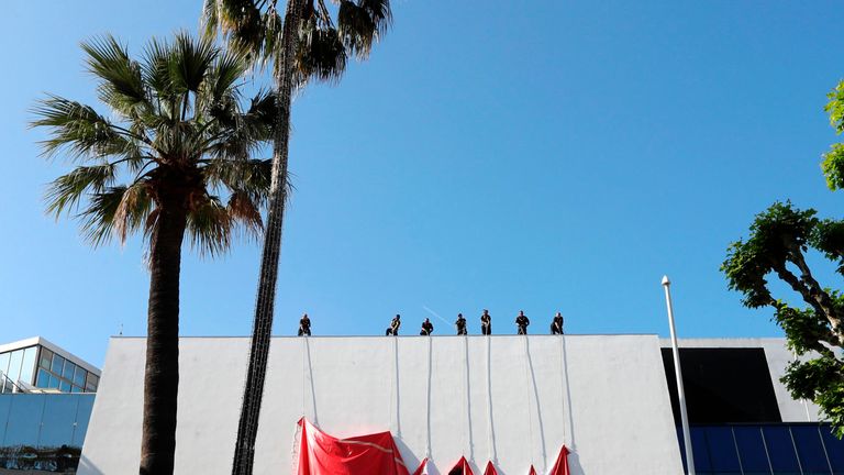 Workers set up a banner of the official poster of the 70th Cannes Film Festival on the facade of the Palais des Festivals 
