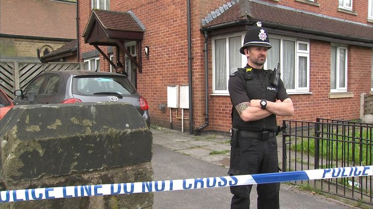 Police officers guard house raided as part of investigation into bomb attack