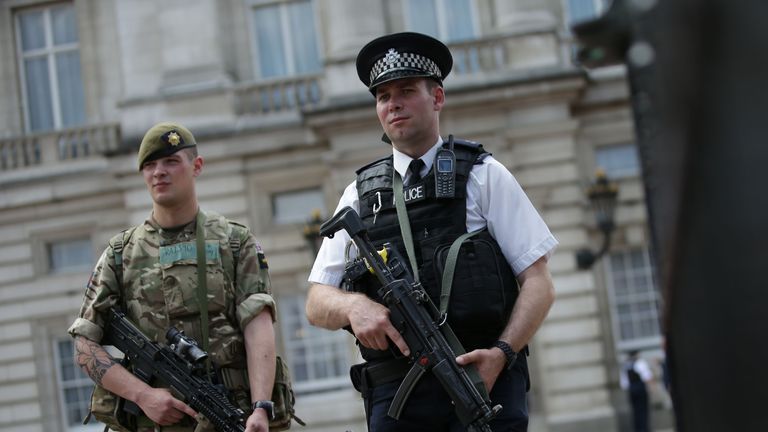 A solider and armed policeman guard Buckingham Palace