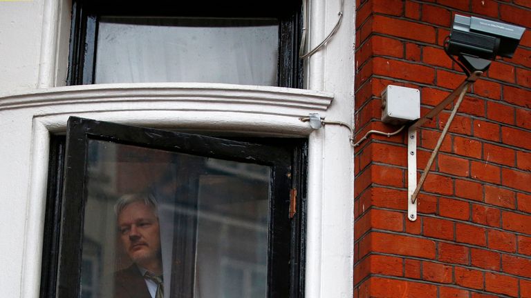 Julian Assange looks outside the window of the Ecuadorian embassy