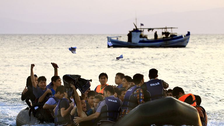 Migrants onboard an overcrowded dinghy arrive at a beach on the Greek island of Kos