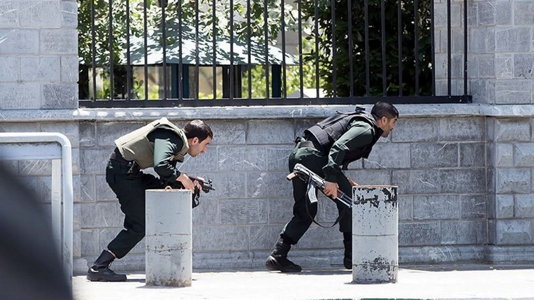 Members of Iranian forces take cover during an attack on the Iranian parliament in central Tehran