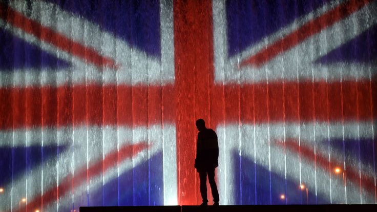 A man stands in front of a fountain illuminated with the colours of the United Kingdom flag on May 23, 2017, in Zagreb