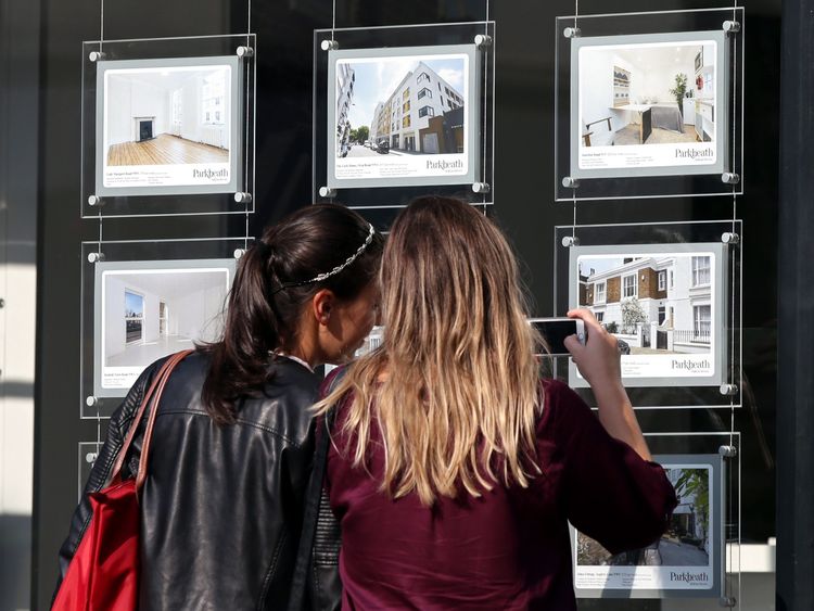 Two women looking in an estate agents window at the houses on offer