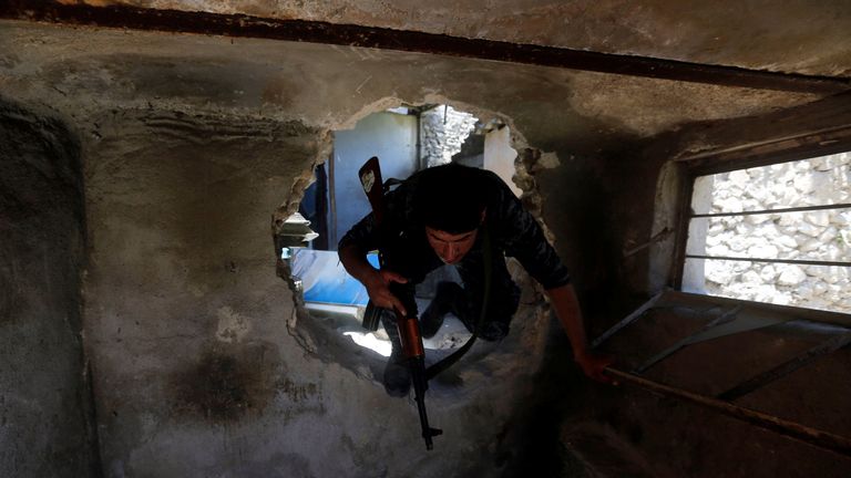 A member of Iraqi Federal Police crosses from one house to another through a hole in the wall at the frontline in the Old City of Mosul
