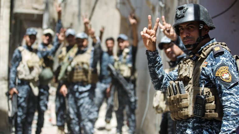 Members of the Iraqi federal police raise the victory gesture while advancing through the Old City of Mosul 