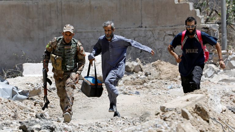 An Iraqi soldier and civilians run to avoid snipers of the Islamic State militants