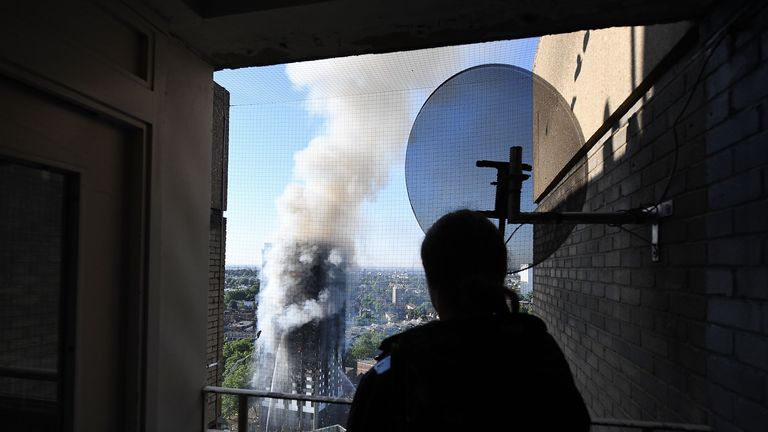 A man watches as smoke continues to rise from the building after a huge fire engulfed the 24 story Grenfell Tower in Latimer Road, West London 