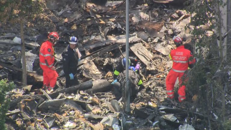Officials pick through the debris surrounding Grenfell Tower 