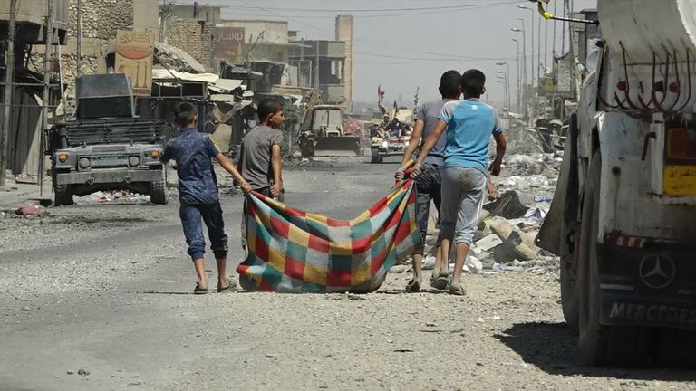 Boys in west Mosul carrying their possessions in a rug