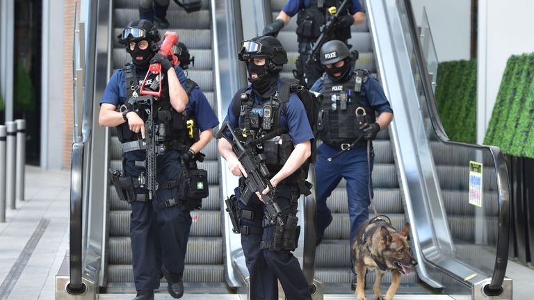 Armed police descend an escalator at the foot of the Shard outside London Bridge station