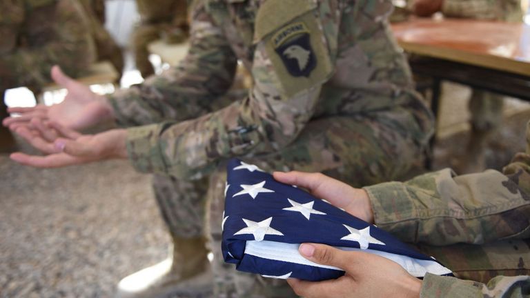 A US soldier holds the national flag in Lashkar Gah in the Afghan province of Helmand