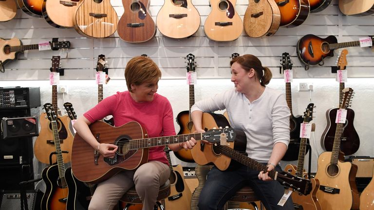 SNP leader Nicola Sturgeon and MP for Paisley and Renfrewshire South Mhairi Black play guitars in a shop while campaigning for the General Election on Wellmeadow Street