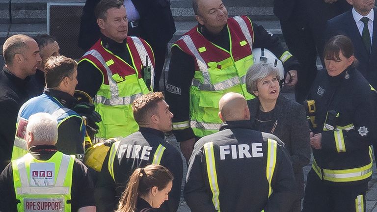 Theresa May is briefed by the emergency services at the scene in north Kensington