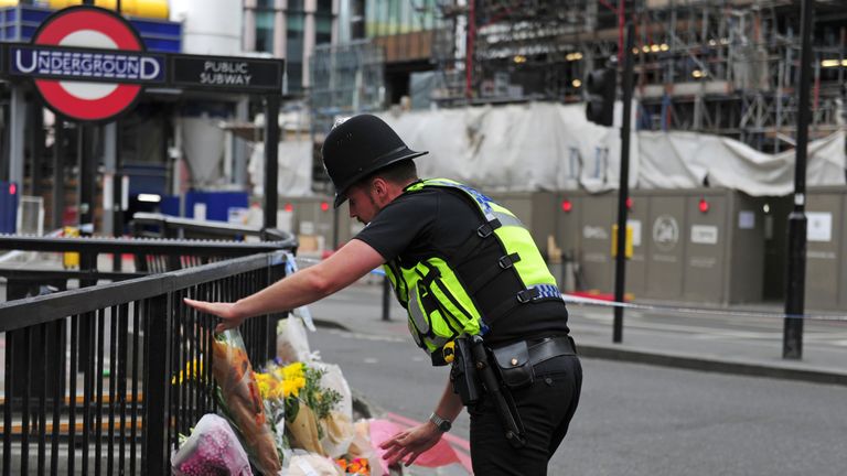 A police officer lays flowers passed to him by members of the public on London Bridge