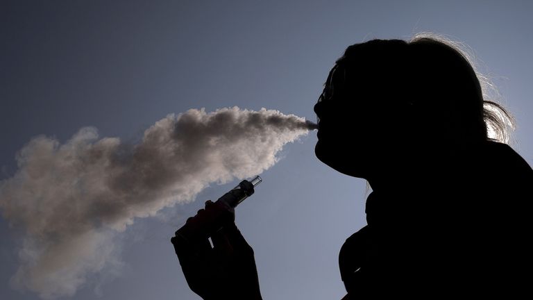 A woman exhales vapour from an e-cigarette