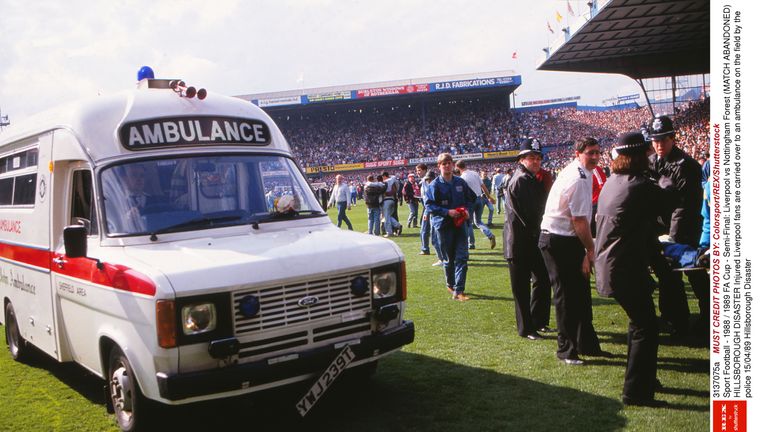 Injured Liverpool fans are carried over to an ambulance on the field by the police