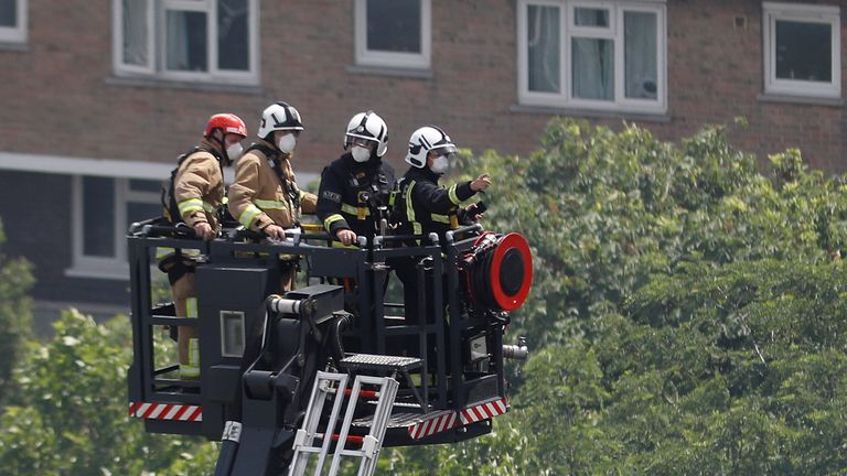 Firefighters use a hydraulic lift to inspect the tower block