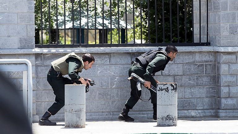 Members of Iranian forces take cover during an attack on the Iranian parliament in central Tehran