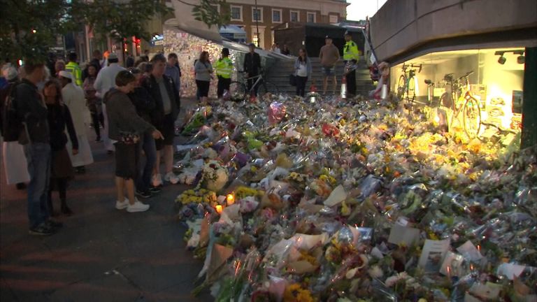 People look at the flowers a week on from the attack that killed eight people