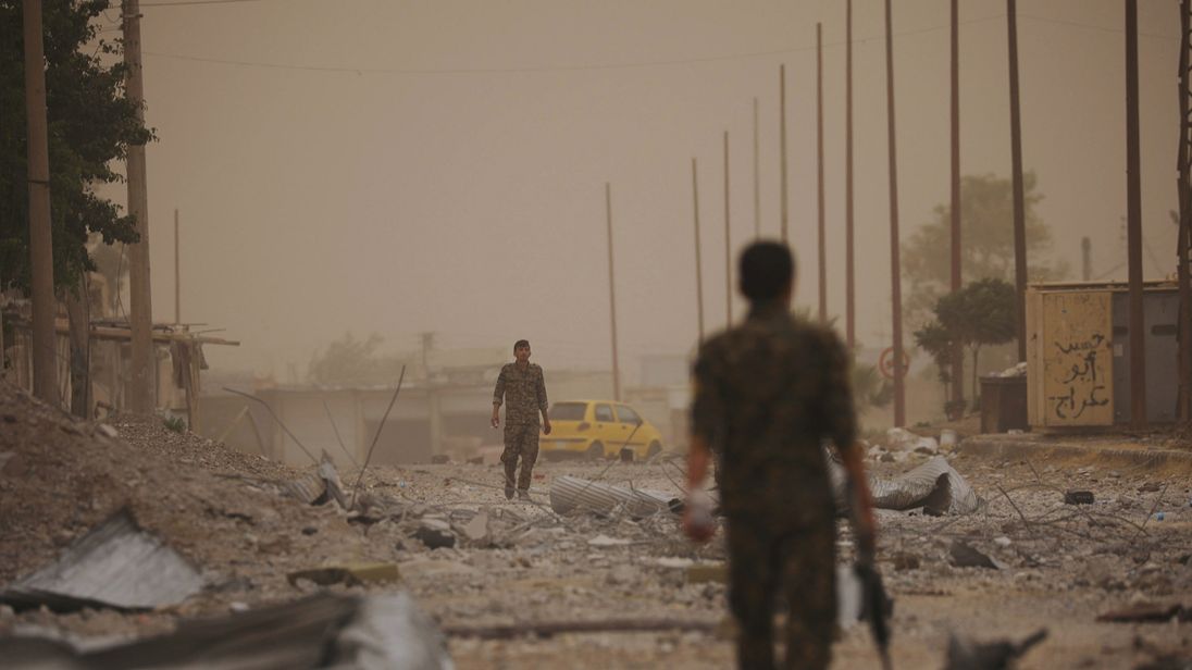 Syrian Democratic Forces (SDF) fighters walk on the rubble of a damaged street in the Raqqa's al-Sanaa industrial neighbourhood, Syria June 14, 2017. Picture taken June 14, 2017. REUTERS/Rodi Said
