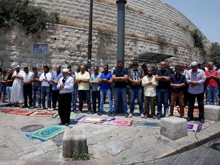 Palestinian Muslim worshippers pray outside Lions' Gate, a main entrance to the Al Aqsa mosque compound