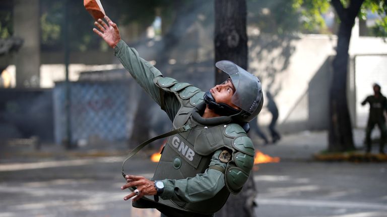 A member of the riot security force throws a piece of brick