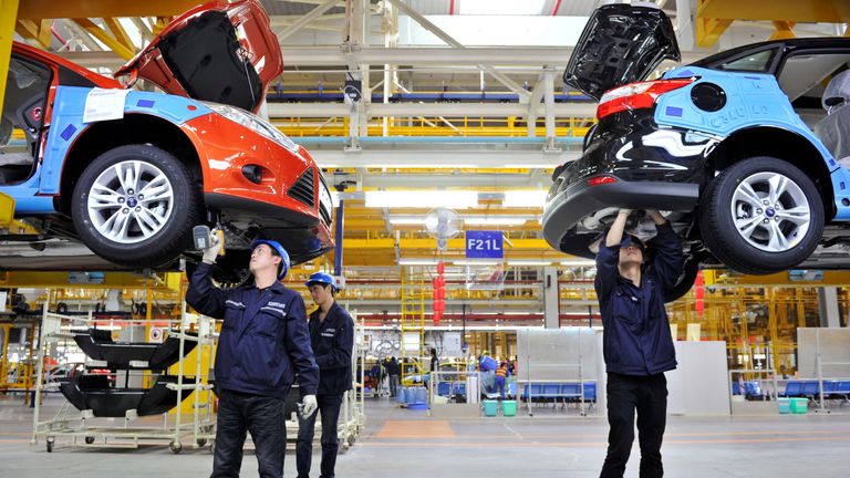 Employees install car components at a Ford manufacturing plant in China