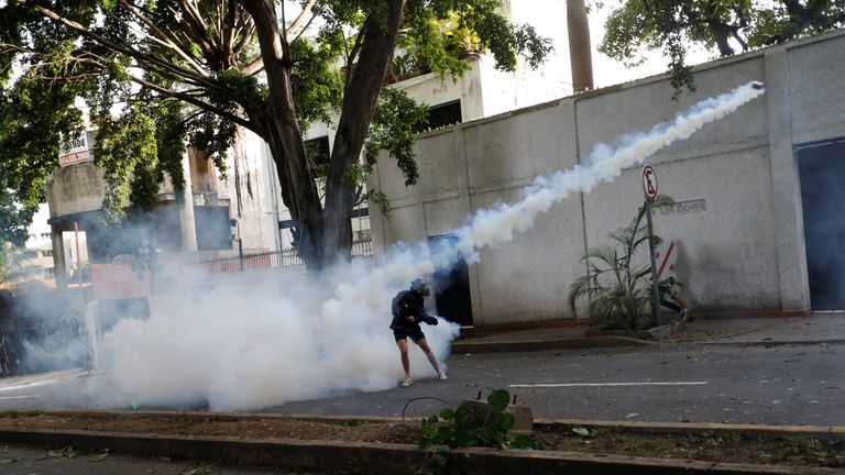A demonstrator throws back a tear gas canister during clashes