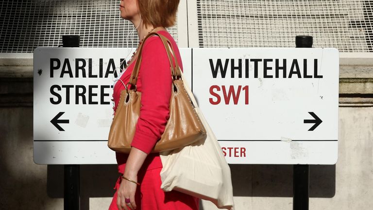 A pedestrian walks past a sign in Whitehall