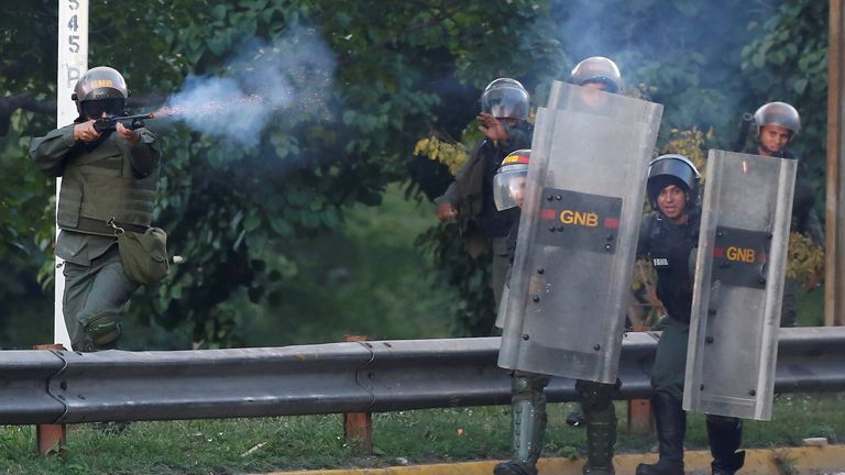 A riot security force member fires his weapon 