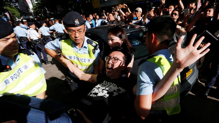 A pro-democracy activist is detained by police as he takes part in a protest