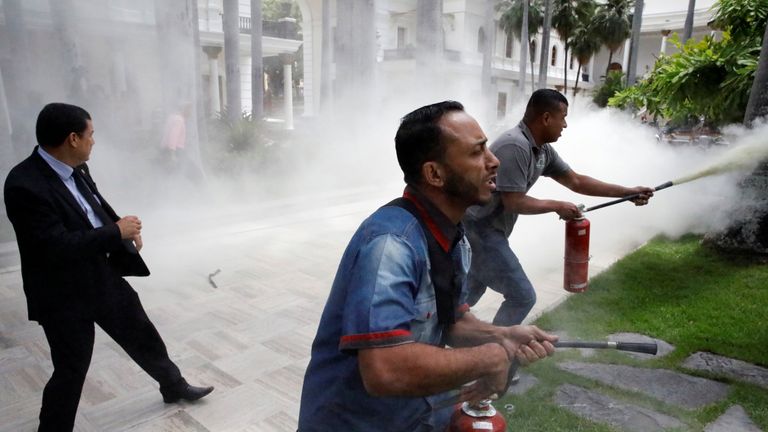 People use fire extinguishers during clashes with government supporters outside the National Assembly