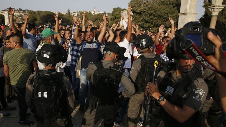 Palestinians flash the victory gesture and shout slogans in front of Israeli security forces